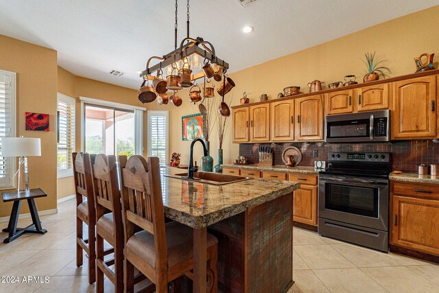 kitchen featuring a sink, stainless steel microwave, light tile patterned floors, and range with electric cooktop