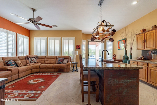 kitchen featuring pendant lighting, light tile patterned floors, sink, a kitchen island with sink, and a breakfast bar area