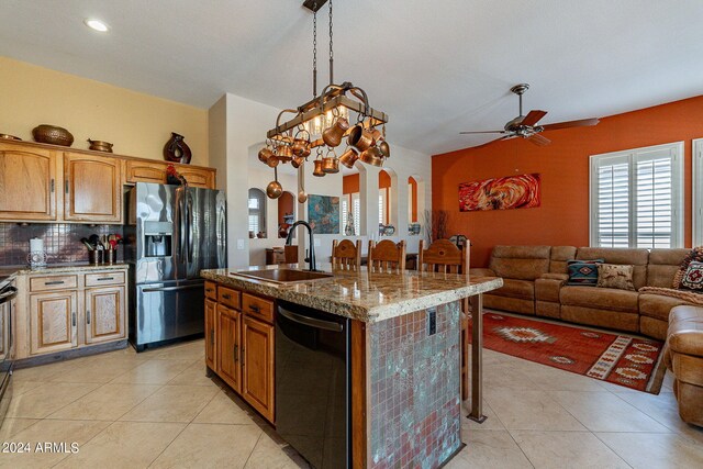 kitchen with a sink, arched walkways, light stone counters, a ceiling fan, and black appliances