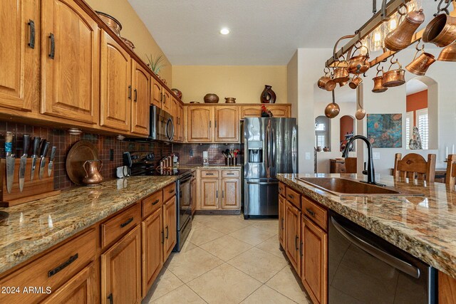 kitchen with light stone countertops, a sink, dishwasher, refrigerator with ice dispenser, and black range with electric stovetop