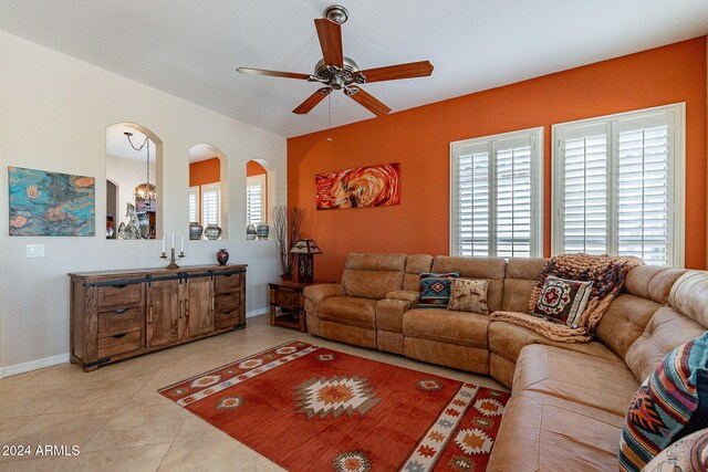 living room with baseboards, a ceiling fan, and arched walkways
