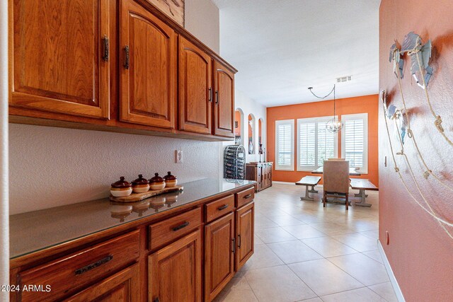 kitchen with brown cabinetry, pendant lighting, baseboards, and arched walkways