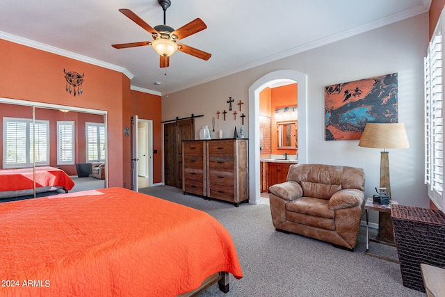 carpeted bedroom featuring arched walkways, ceiling fan, a barn door, connected bathroom, and ornamental molding