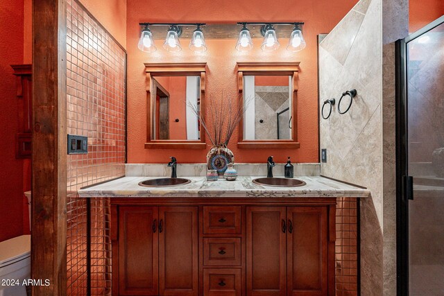 bathroom featuring a sink, a stall shower, and double vanity