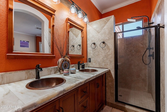 bathroom featuring double vanity, a shower stall, ornamental molding, and a sink