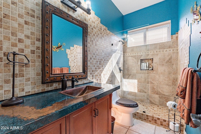 full bathroom featuring toilet, tile patterned floors, a tile shower, and vanity