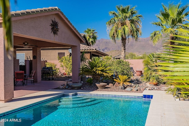 pool featuring a ceiling fan, a patio area, and a mountain view