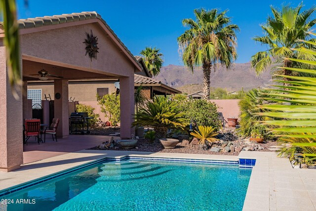 pool featuring a patio, a ceiling fan, a mountain view, and fence