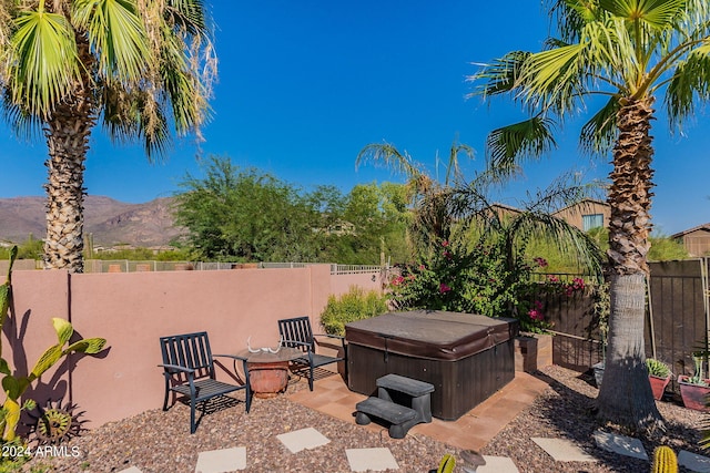 view of patio / terrace with a fenced backyard, a mountain view, and a hot tub