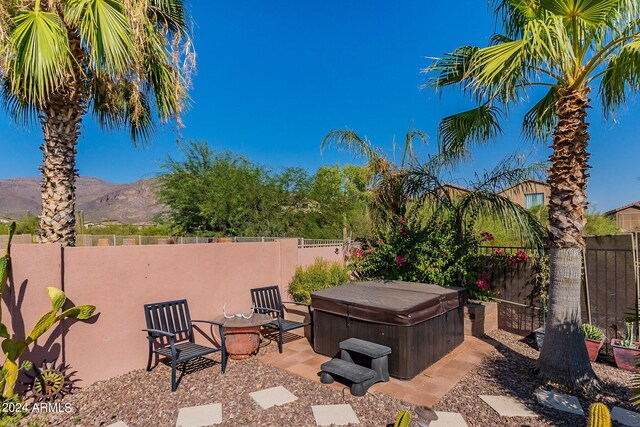 view of patio / terrace featuring a hot tub, a mountain view, and a fenced backyard