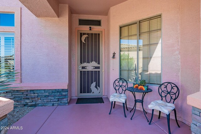 doorway to property featuring covered porch and stucco siding