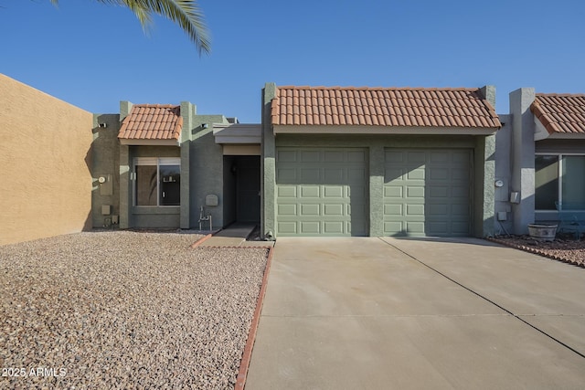 view of front of house featuring concrete driveway, a tile roof, an attached garage, and stucco siding