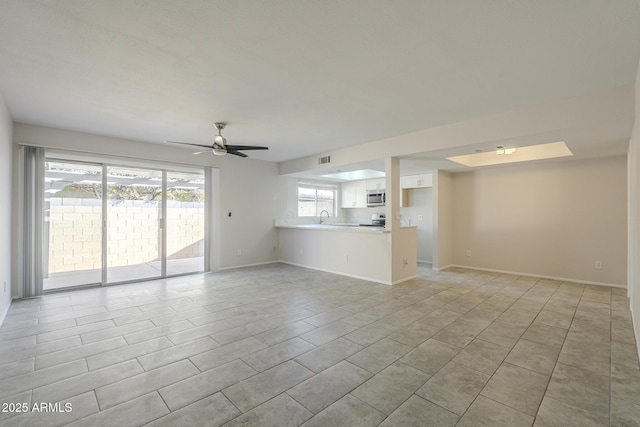 unfurnished living room featuring light tile patterned floors, a sink, visible vents, a ceiling fan, and baseboards