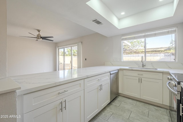 kitchen with light stone counters, stainless steel appliances, visible vents, a sink, and a peninsula