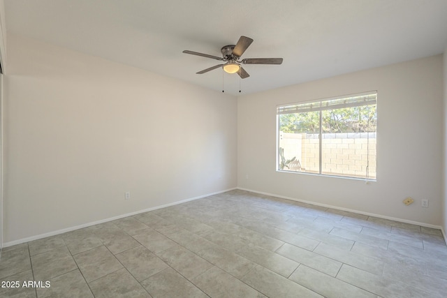 spare room with ceiling fan and baseboards