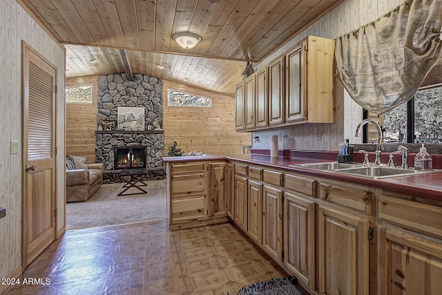 kitchen featuring wood ceiling, vaulted ceiling, wood walls, a fireplace, and sink