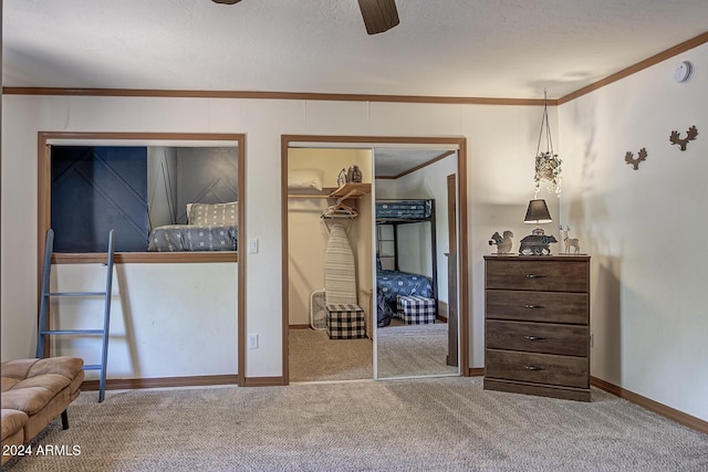 carpeted bedroom with ceiling fan, a spacious closet, ornamental molding, and a closet