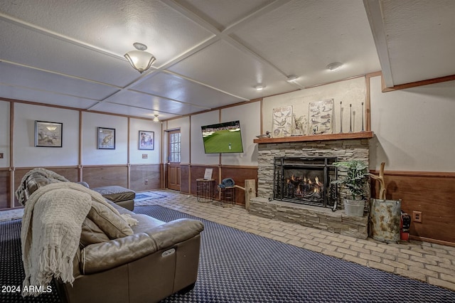 living room featuring wood walls, a textured ceiling, and a fireplace