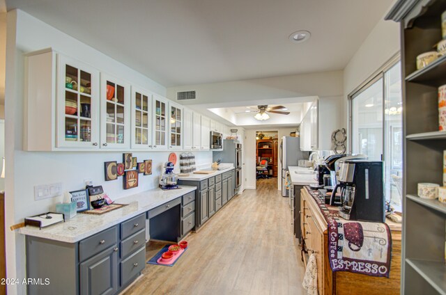 kitchen featuring light wood-type flooring, light stone counters, white cabinets, gray cabinetry, and ceiling fan