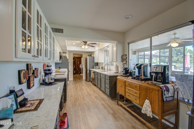 kitchen with light hardwood / wood-style floors, stainless steel appliances, light stone counters, and white cabinets