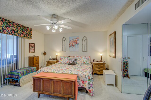 carpeted bedroom with ceiling fan and a textured ceiling