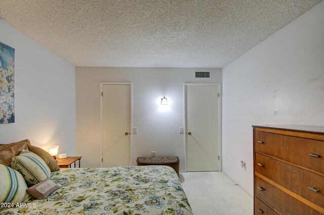 bedroom featuring light colored carpet, a textured ceiling, and a closet