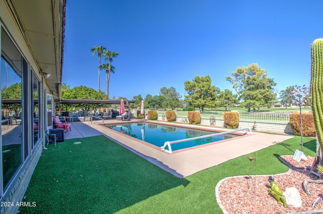 view of pool with a diving board, a yard, and a patio