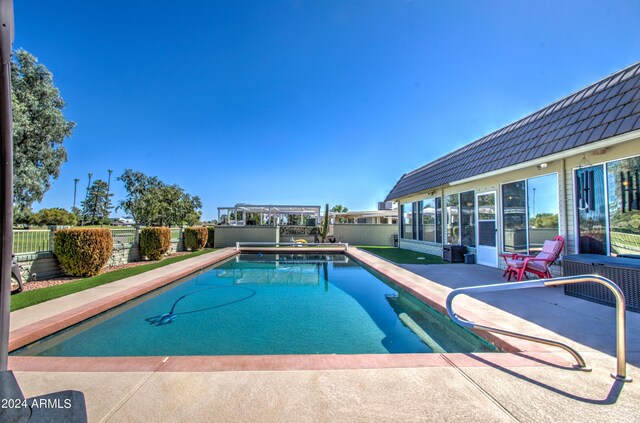 view of swimming pool with a sunroom and a patio area