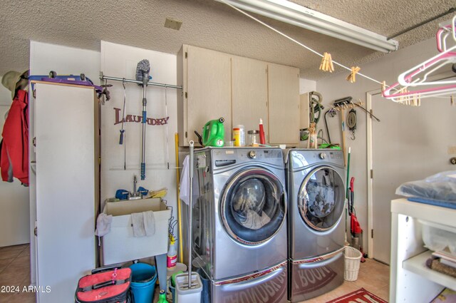 clothes washing area featuring a textured ceiling, light tile patterned flooring, and separate washer and dryer