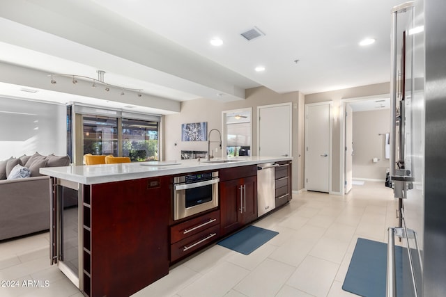 kitchen featuring light tile patterned floors, stainless steel appliances, a kitchen island with sink, and sink