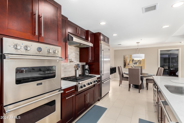 kitchen featuring decorative backsplash, appliances with stainless steel finishes, hanging light fixtures, and sink