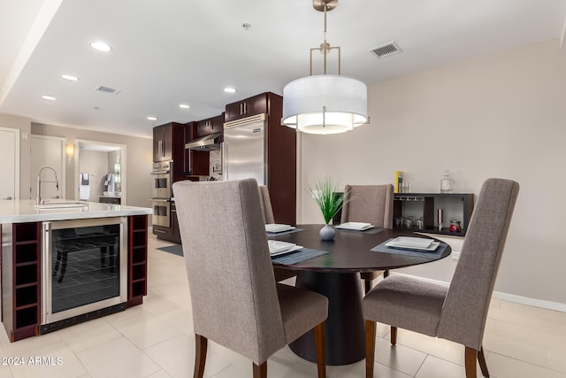 dining space featuring light tile patterned floors, beverage cooler, and sink