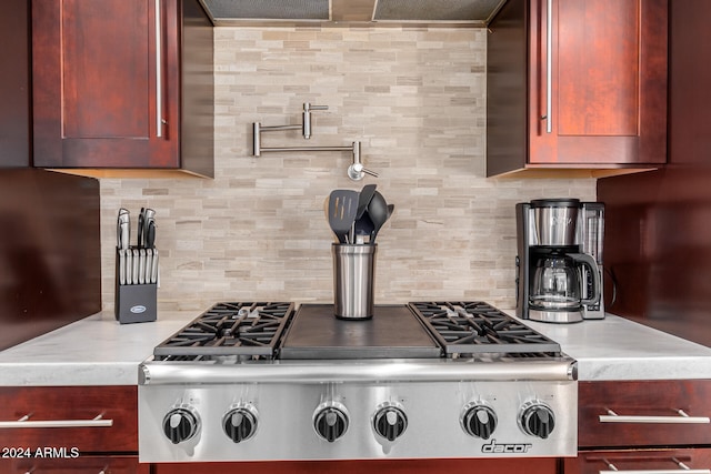 kitchen featuring stainless steel gas stovetop, light stone counters, and tasteful backsplash