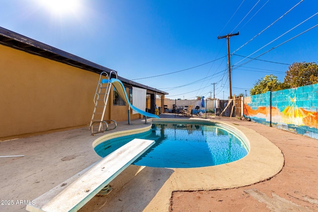 view of pool with a water slide, a diving board, and a patio area