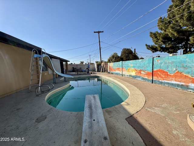 view of swimming pool with a patio, a diving board, and a water slide