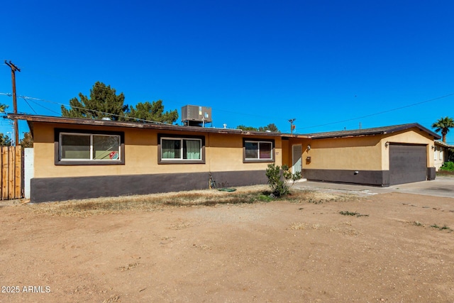 ranch-style home featuring a garage and central AC unit