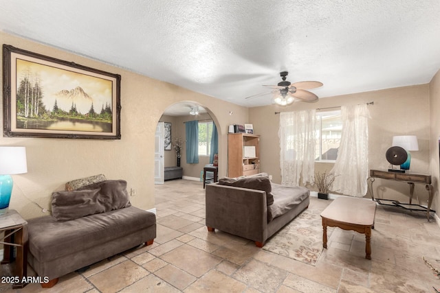 living room with ceiling fan and a textured ceiling