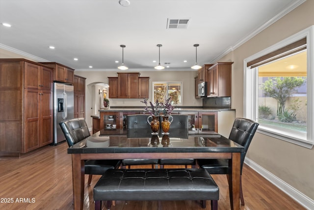 dining area featuring a wealth of natural light, ornamental molding, and wood-type flooring