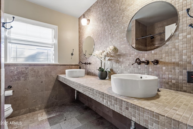 bathroom featuring double sink, tile walls, and toilet