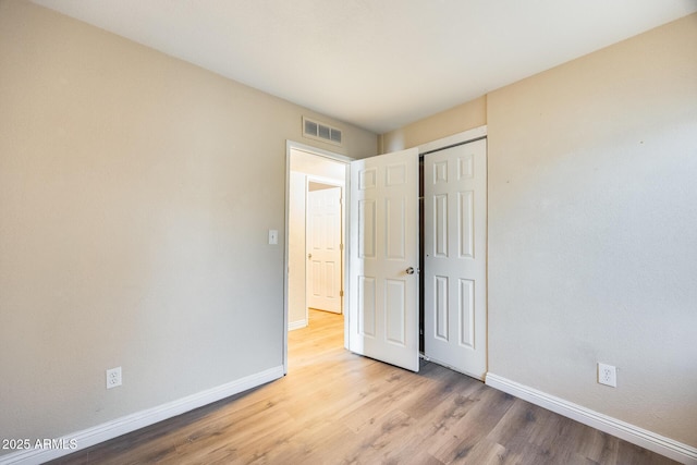 unfurnished bedroom with light hardwood / wood-style flooring and a closet