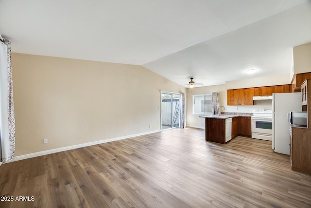 kitchen with white appliances, vaulted ceiling, sink, light hardwood / wood-style flooring, and kitchen peninsula