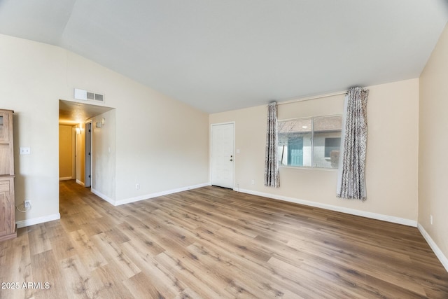 spare room with light wood-type flooring and vaulted ceiling