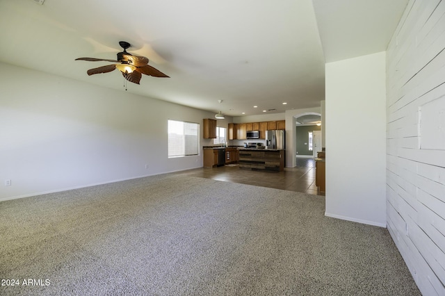 unfurnished living room with dark carpet and ceiling fan