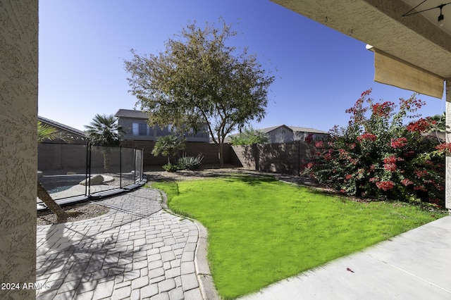 view of yard with a trampoline and a patio