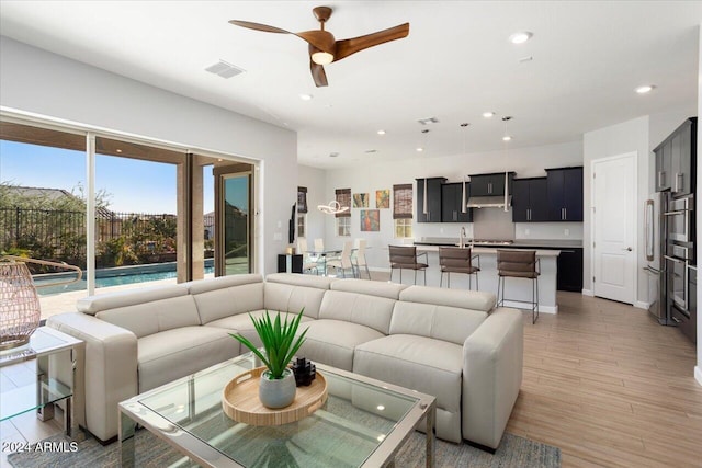 living room with ceiling fan and light hardwood / wood-style flooring