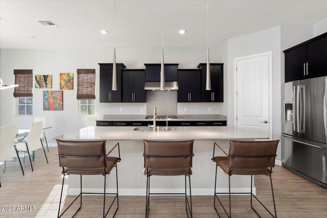 kitchen featuring a center island with sink, light hardwood / wood-style floors, stainless steel refrigerator with ice dispenser, and sink