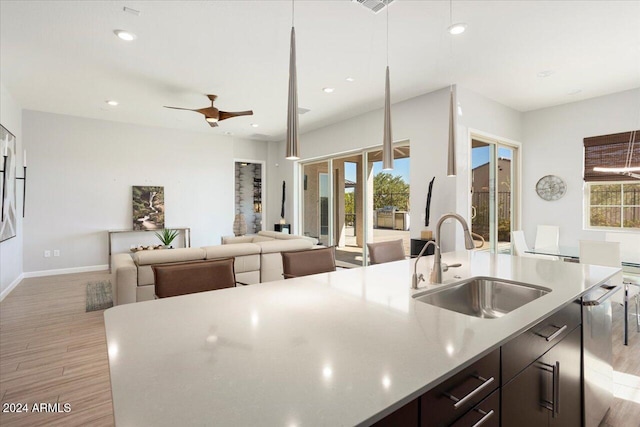 kitchen featuring a wealth of natural light, sink, decorative light fixtures, and light hardwood / wood-style flooring