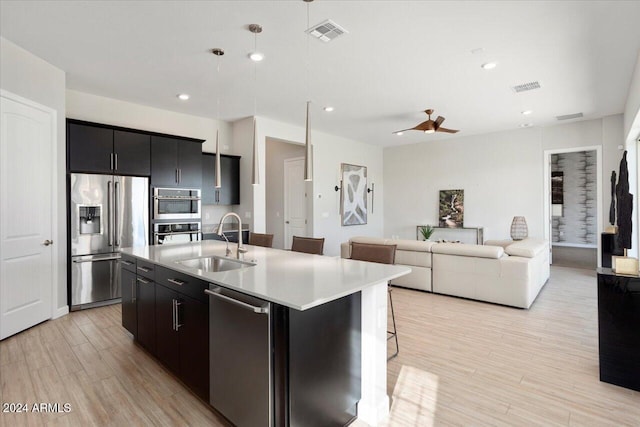 kitchen featuring a breakfast bar, a center island with sink, sink, ceiling fan, and stainless steel appliances