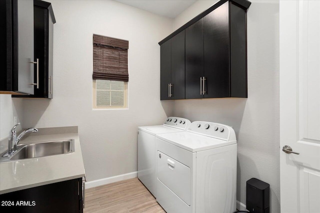 laundry room featuring light hardwood / wood-style floors, cabinets, sink, and washing machine and clothes dryer