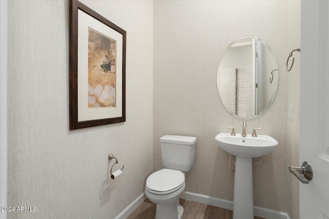 bathroom with hardwood / wood-style flooring, toilet, and sink